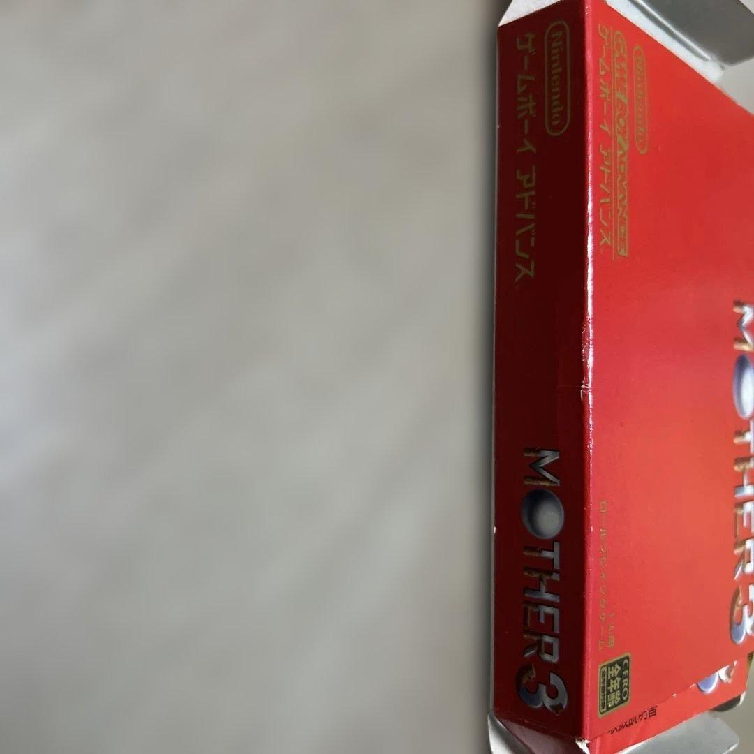 Game Boy Advance MOTHER3 game cartridge with original box and manual showing wear and aging signs