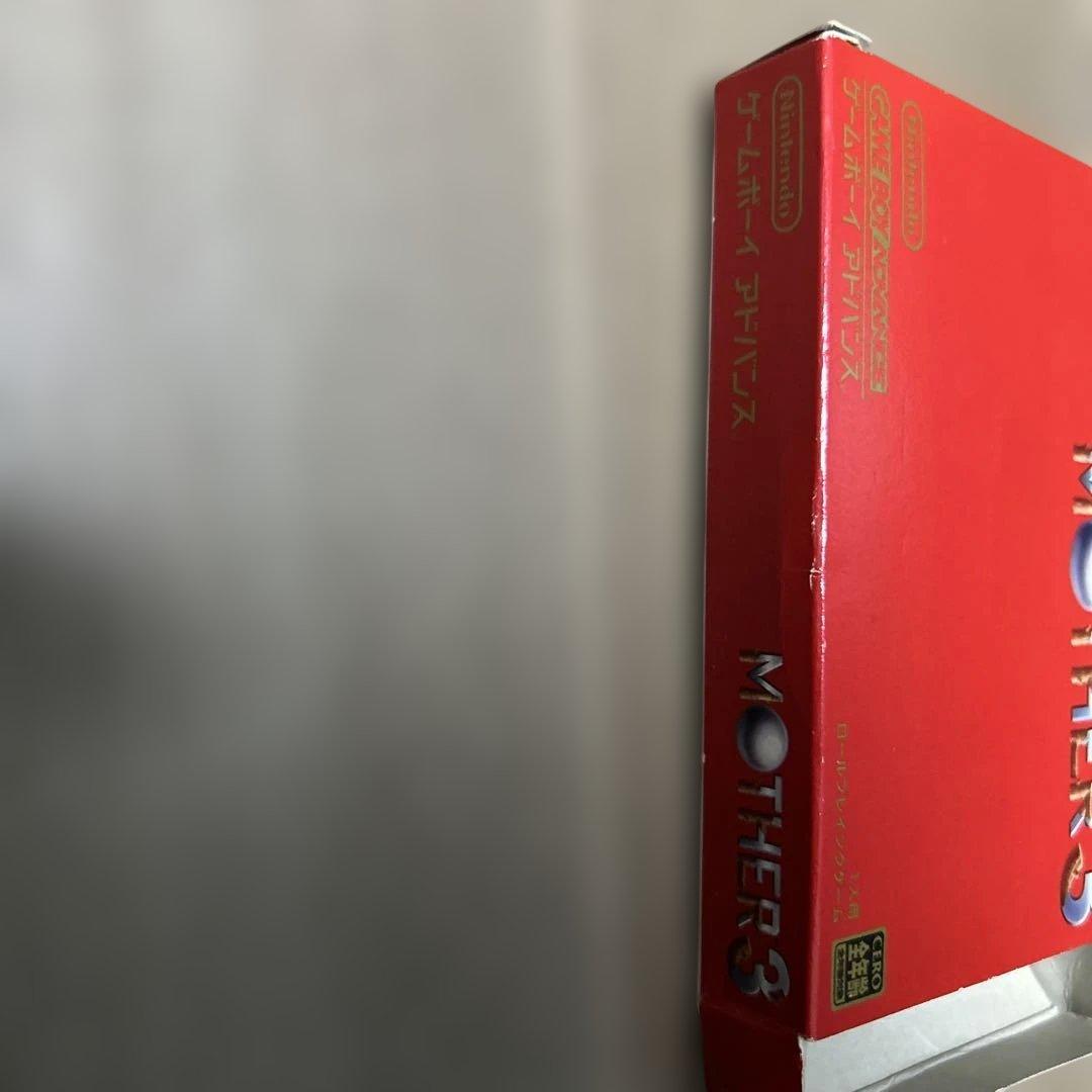Game Boy Advance MOTHER3 game cartridge with original box and manual showing wear and aging signs