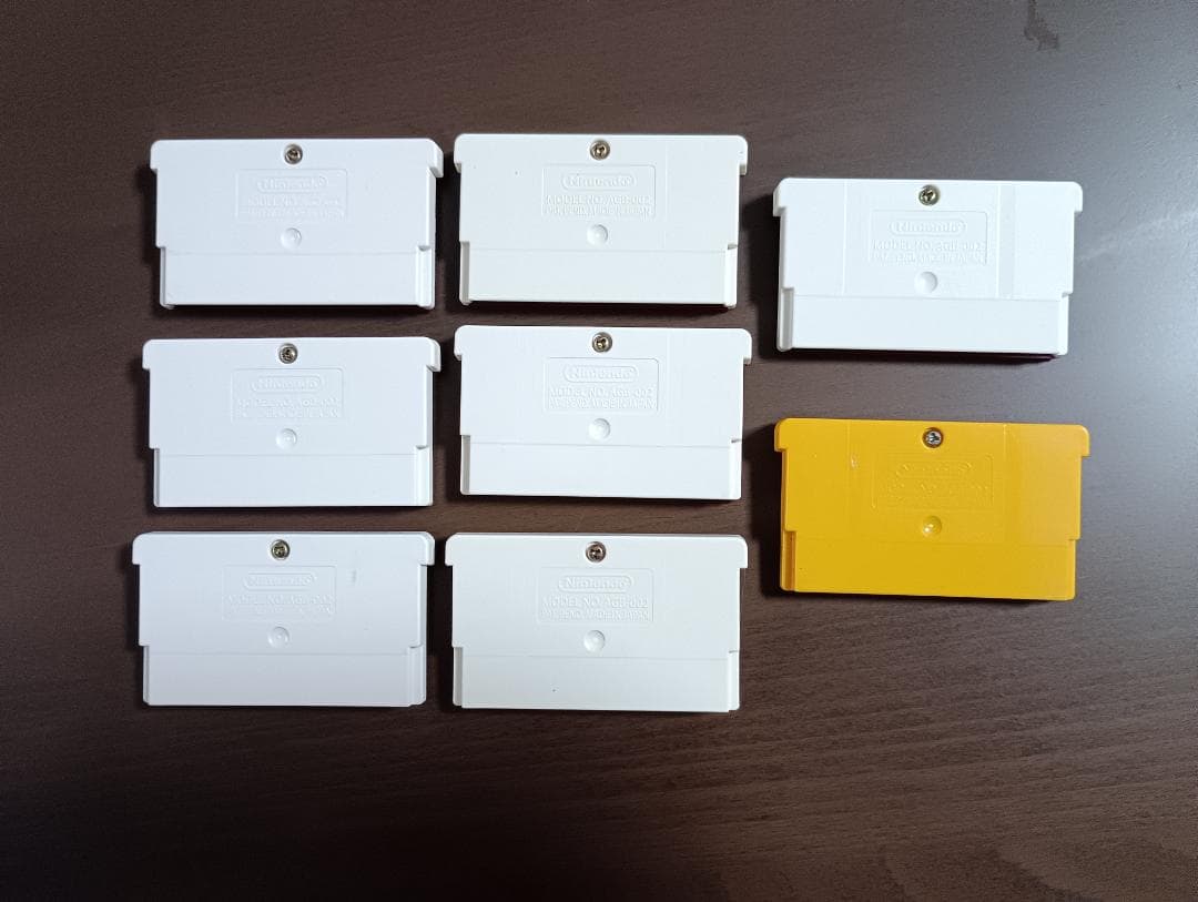 Famicom Mini Advance console with 8 classic game cartridges including Takahashi Meijin's Adventure Island and Bomberman