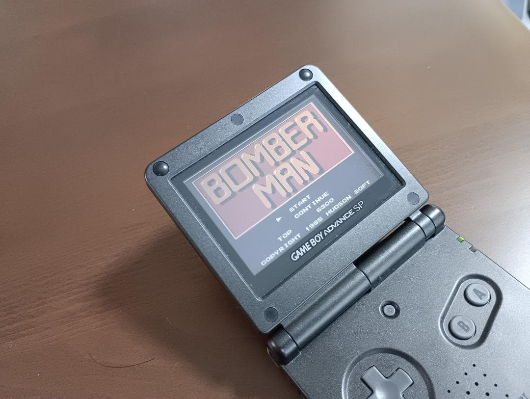 Famicom Mini Advance console with 8 classic game cartridges including Takahashi Meijin's Adventure Island and Bomberman