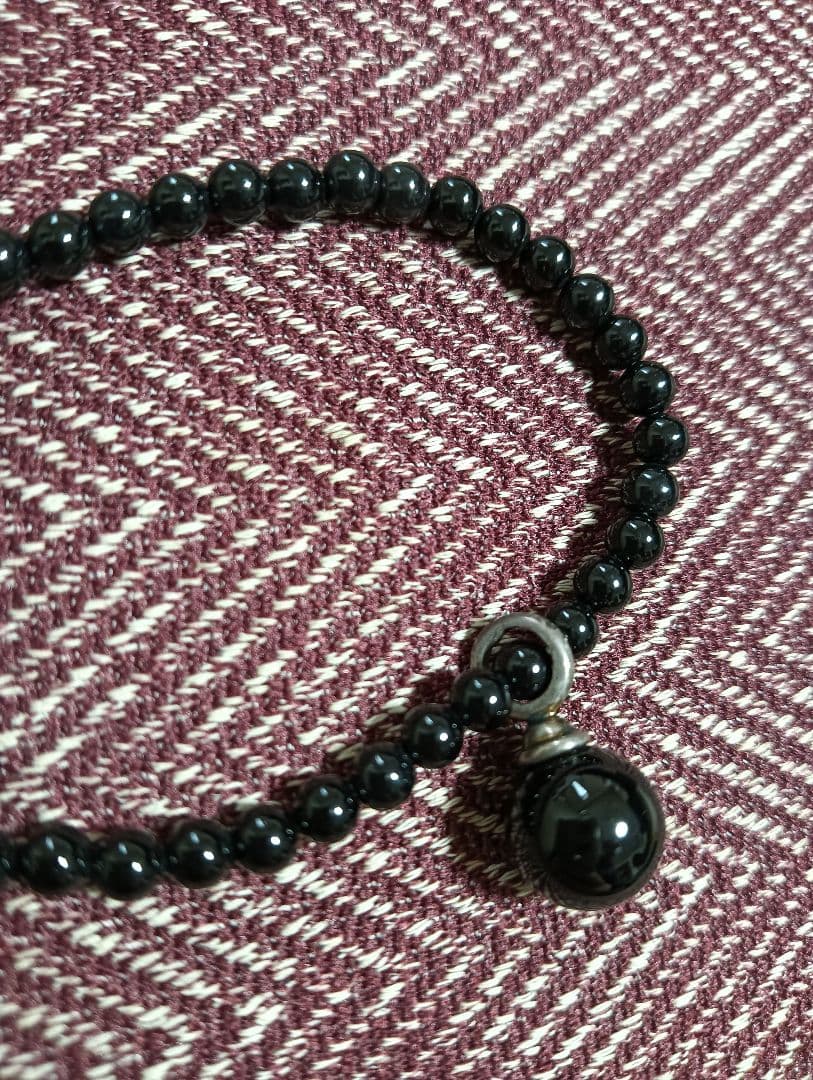 Agete Onyx Necklace with 4mm beads and a 9-10mm silver charm on a white background