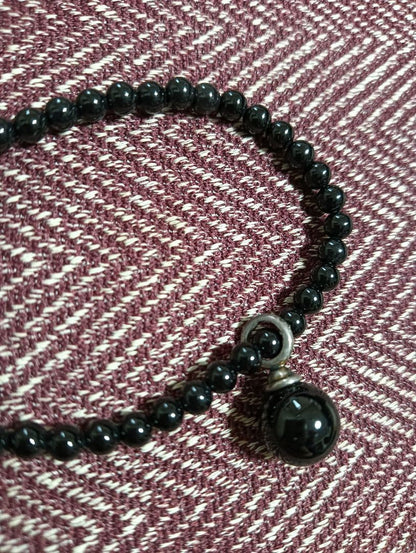 Agete Onyx Necklace with 4mm beads and a 9-10mm silver charm on a white background