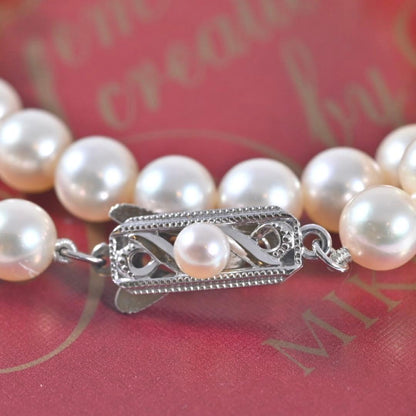 Highest-grade Mikimoto K14 Akoya pearl necklace with 7mm round pearls and white gold clasp on a white background