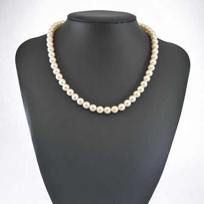 Highest-grade Mikimoto K14 Akoya pearl necklace with 7mm round pearls and white gold clasp on a white background