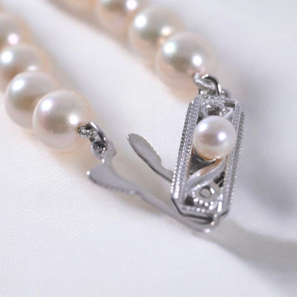 Highest-grade Mikimoto K14 Akoya pearl necklace with 7mm round pearls and white gold clasp on a white background