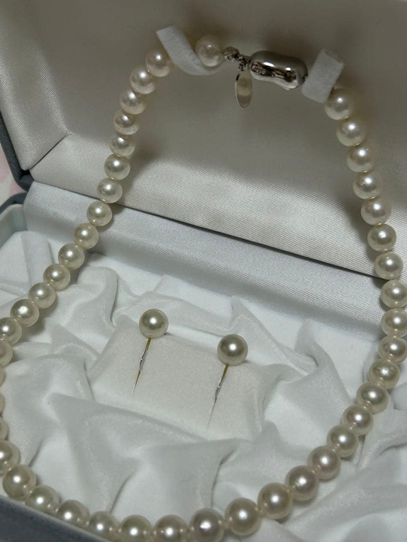 Akoya pearl choker necklace with matching pair of pearl earrings on white background