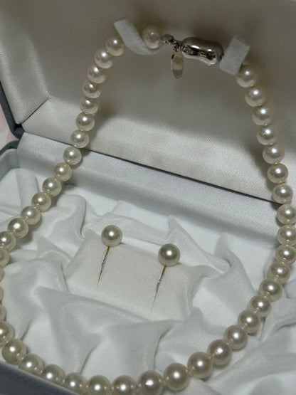 Akoya pearl choker necklace with matching pair of pearl earrings on white background