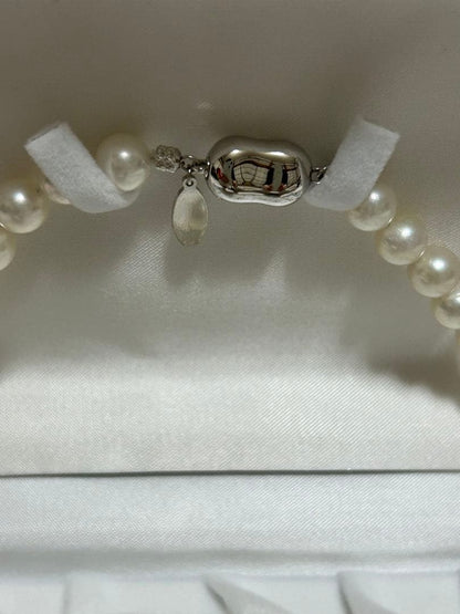 Akoya pearl choker necklace with matching pair of pearl earrings on white background