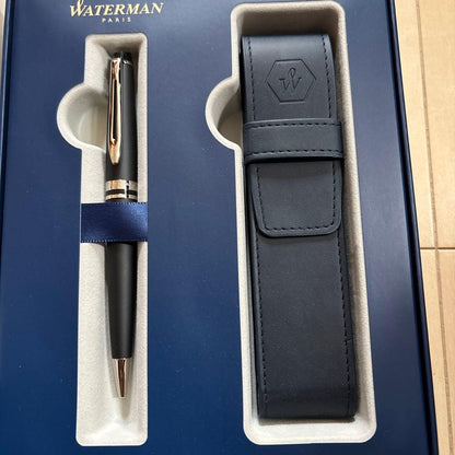 WATERMAN black ballpoint pen alongside its leather case and gift box on a white background