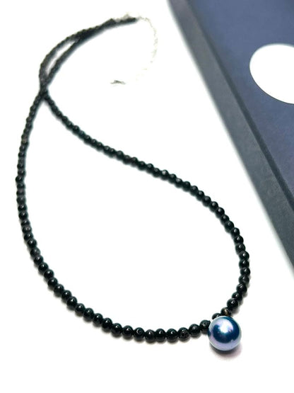 Oomamemono Akoya pearl black tourmaline necklace with round indigo blue pearls on white background