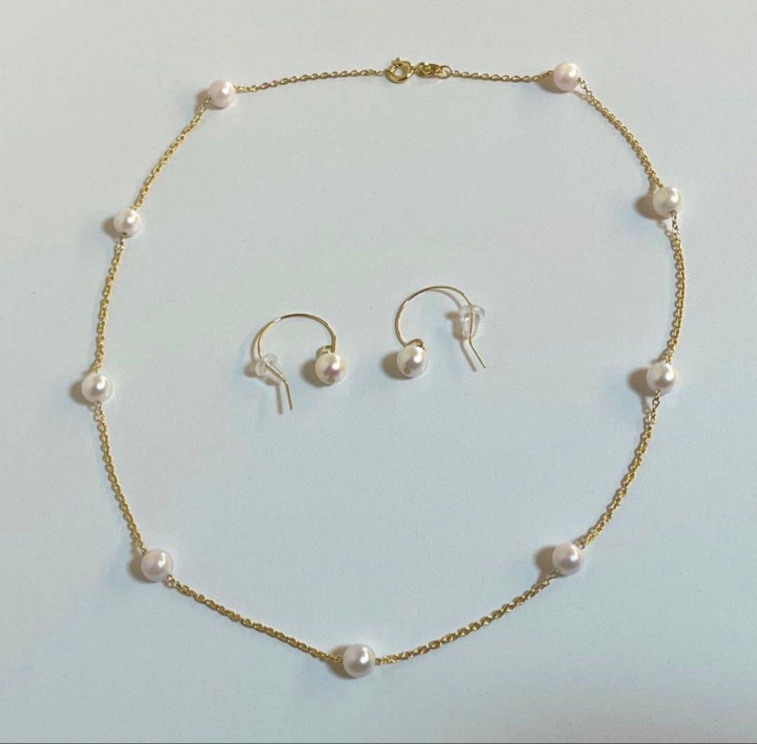 Akoya pearl station necklace with 9 white pink pearls and matching silver hook earrings set on white background