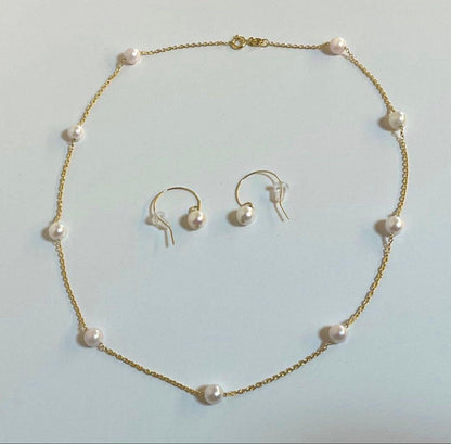 Akoya pearl station necklace with 9 white pink pearls and matching silver hook earrings set on white background
