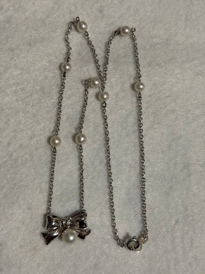 TASAKI elegant silver necklace with lustrous white pearls on a white background