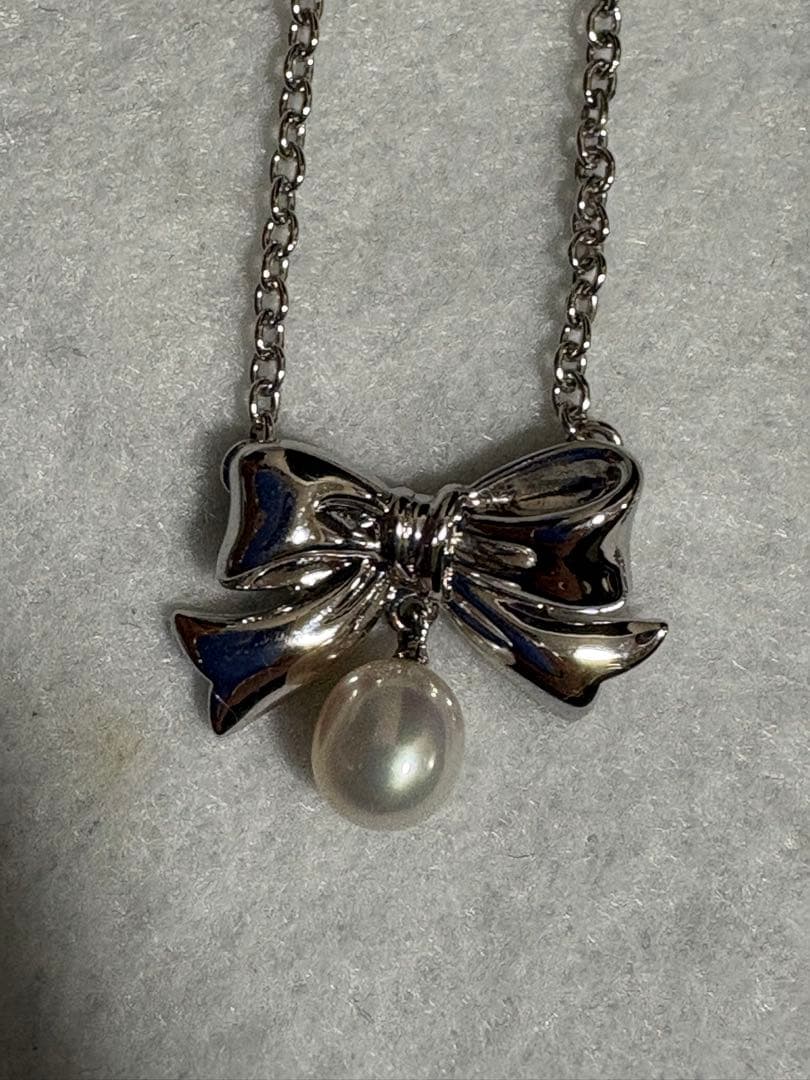 TASAKI elegant silver necklace with lustrous white pearls on a white background