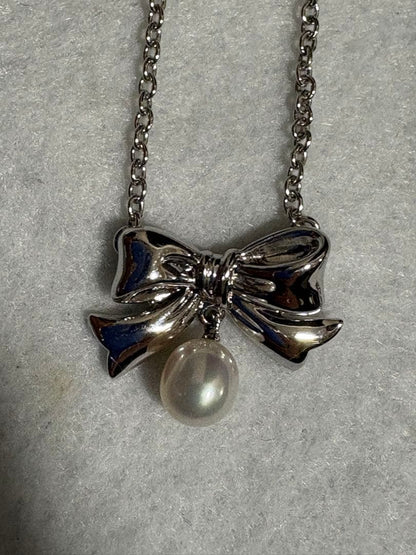 TASAKI elegant silver necklace with lustrous white pearls on a white background
