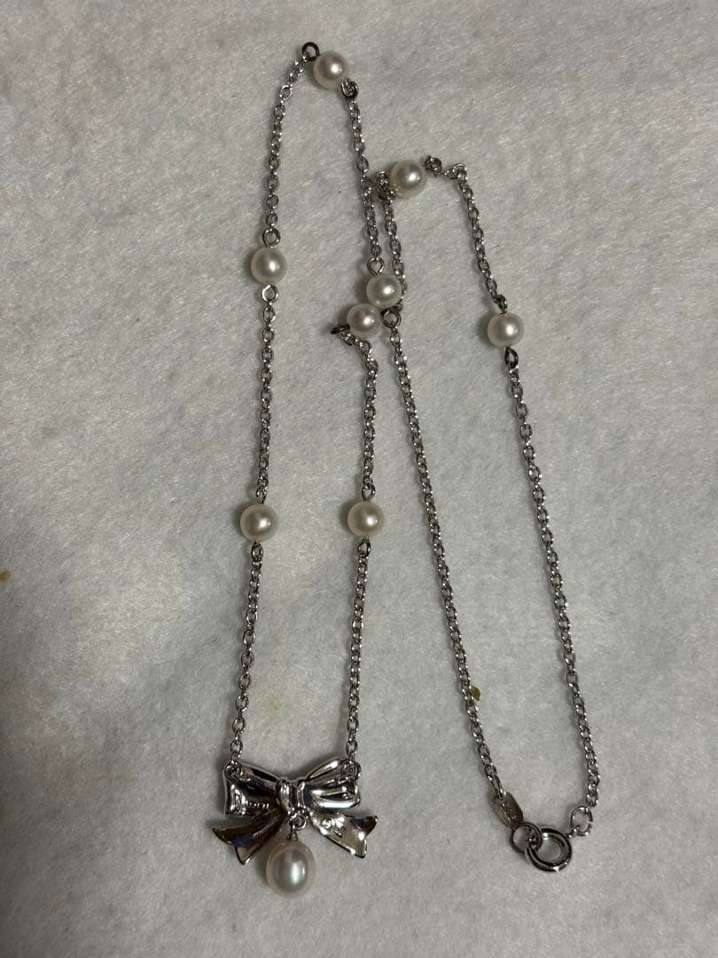 TASAKI elegant silver necklace with lustrous white pearls on a white background