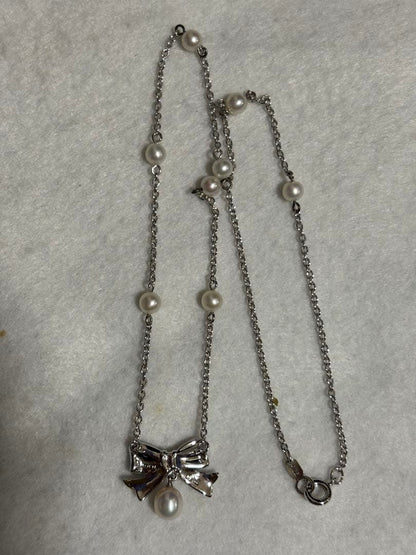 TASAKI elegant silver necklace with lustrous white pearls on a white background