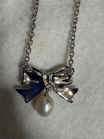 TASAKI elegant silver necklace with lustrous white pearls on a white background