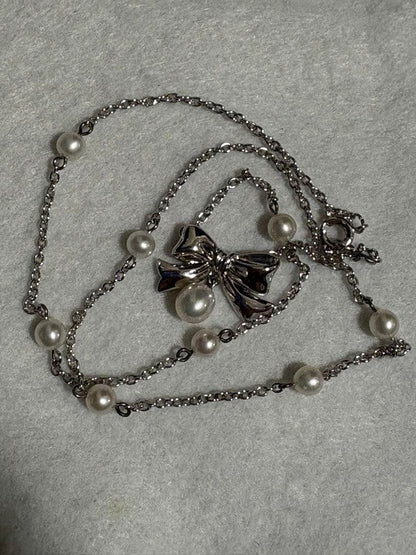 TASAKI elegant silver necklace with lustrous white pearls on a white background