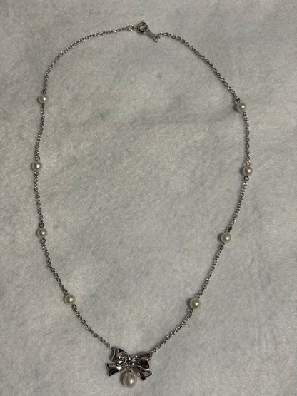 TASAKI elegant silver necklace with lustrous white pearls on a white background