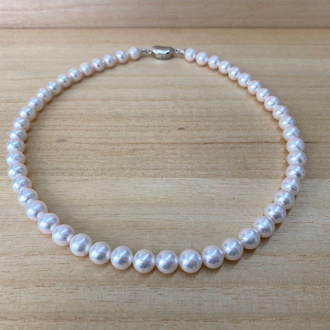 Akoya pearl necklace with 49 iridescent pearls sized 8.0-8.5mm and silver one-touch clasp on white background