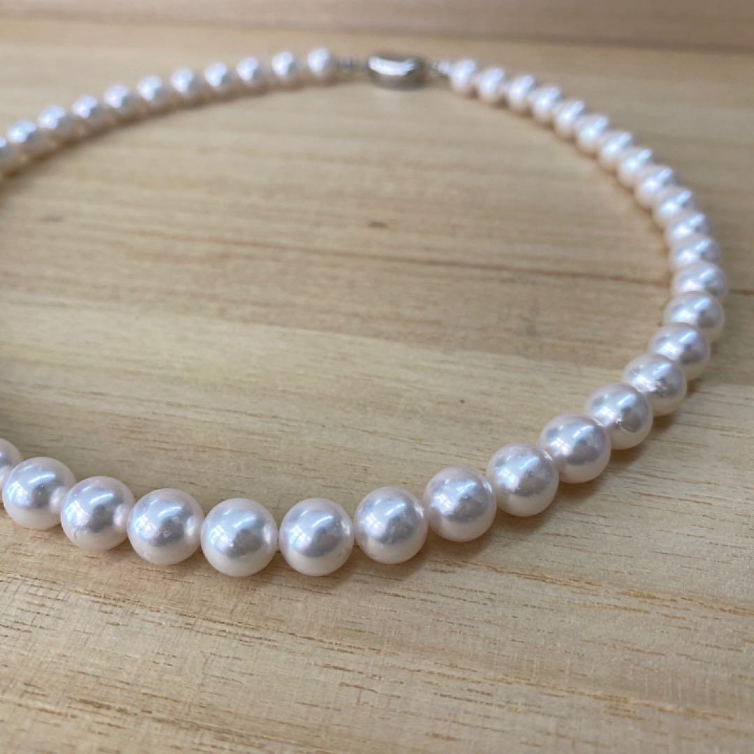 Akoya pearl necklace with 49 iridescent pearls sized 8.0-8.5mm and silver one-touch clasp on white background