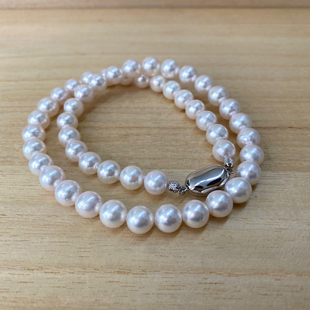 Akoya pearl necklace with 49 iridescent pearls sized 8.0-8.5mm and silver one-touch clasp on white background