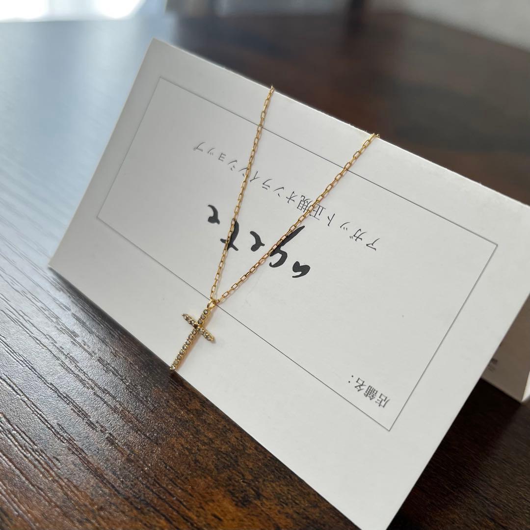 agete K18YG yellow gold diamond cross necklace with reversible milgrain design on a white background