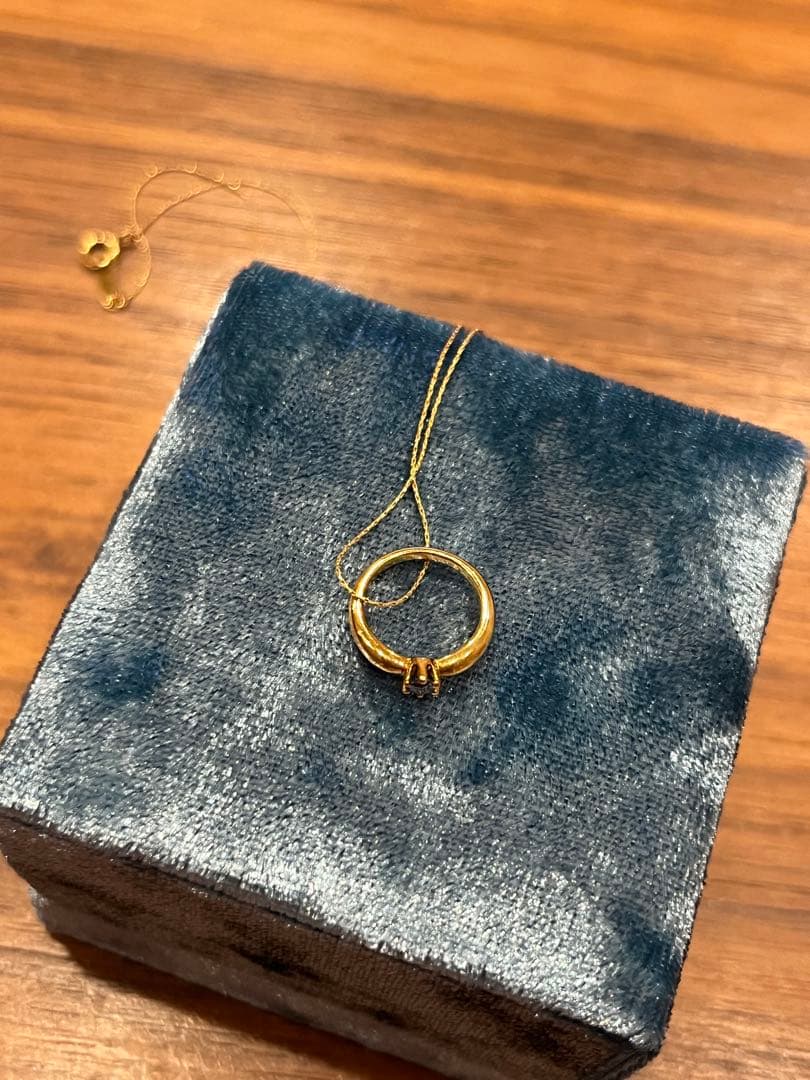Mikimoto gold necklace with a sapphire pendant displayed on a white background