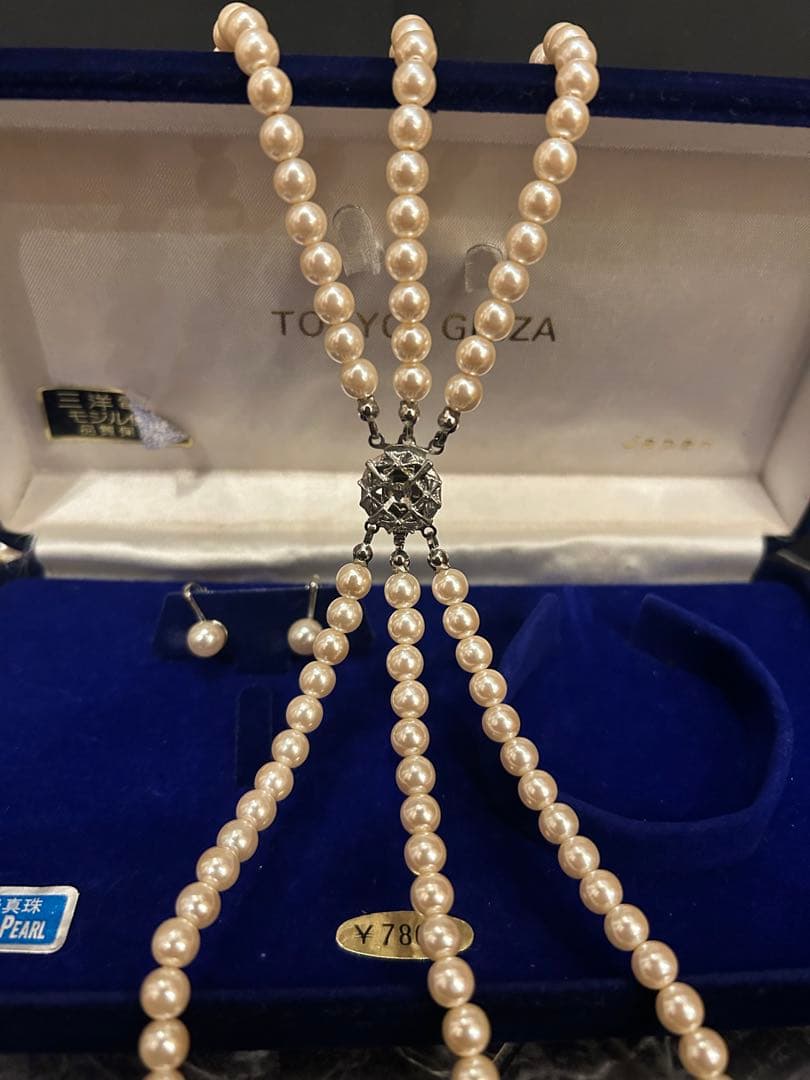Akoya pearl three-strand beige necklace with matching earrings displayed on a white background