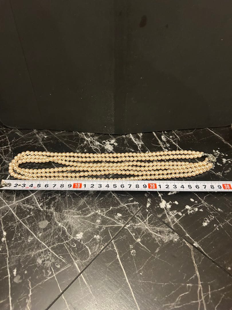 Akoya pearl three-strand beige necklace with matching earrings displayed on a white background