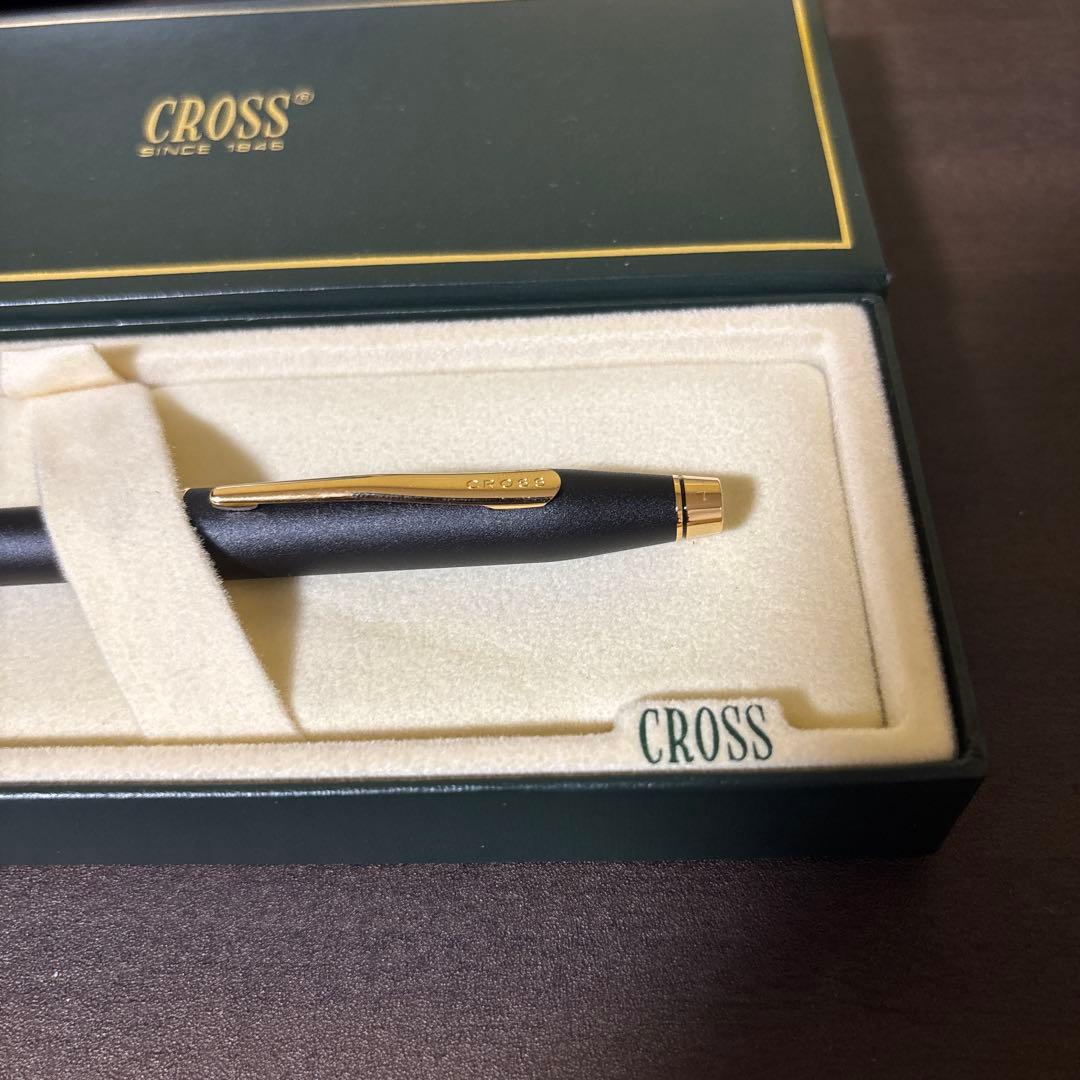 CROSS ballpoint pen with matte black barrel and gold clip lying on white background