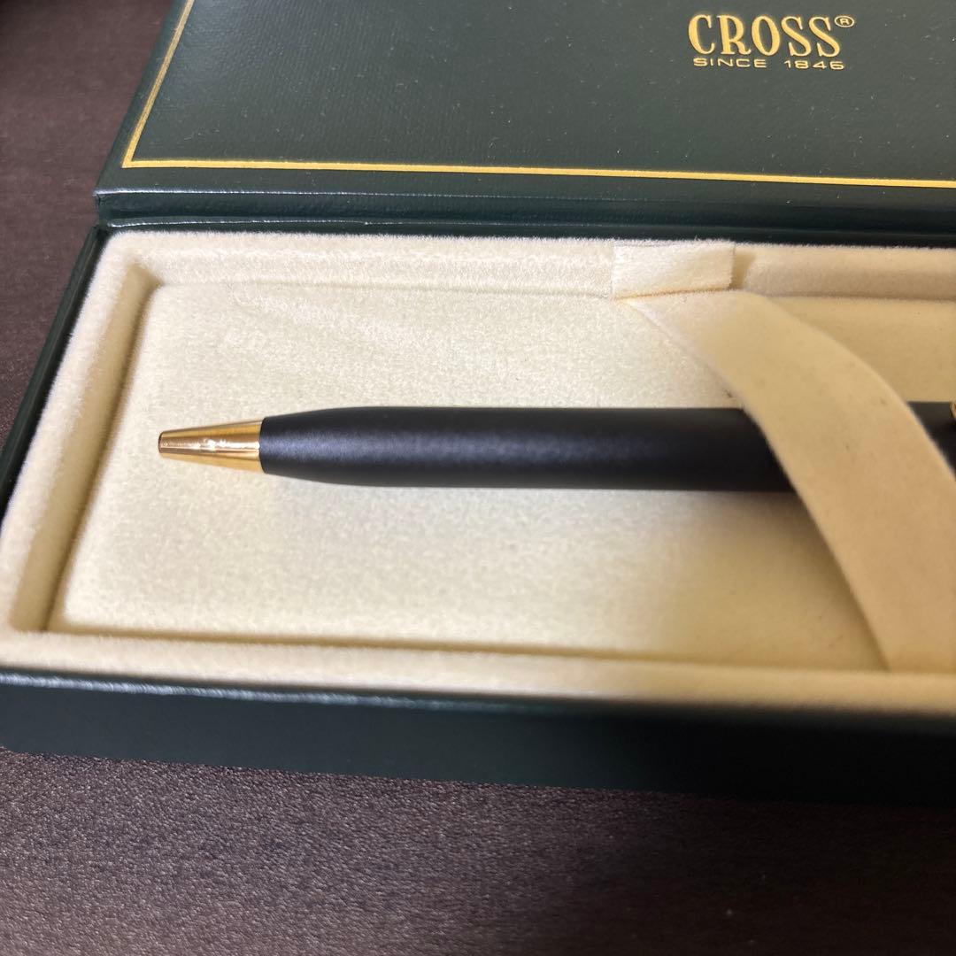 CROSS ballpoint pen with matte black barrel and gold clip lying on white background
