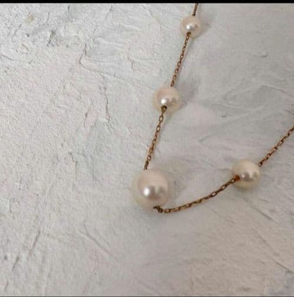 Beautiful K18 gold chain Akoya pearl necklace with 13 round pearls sized 6.5 to 9.5 mm on a white background
