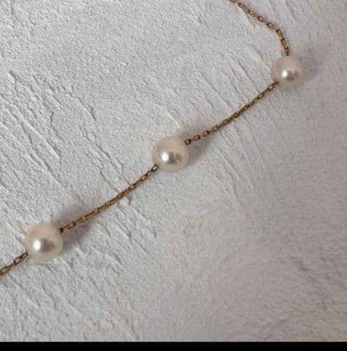 Beautiful K18 gold chain Akoya pearl necklace with 13 round pearls sized 6.5 to 9.5 mm on a white background