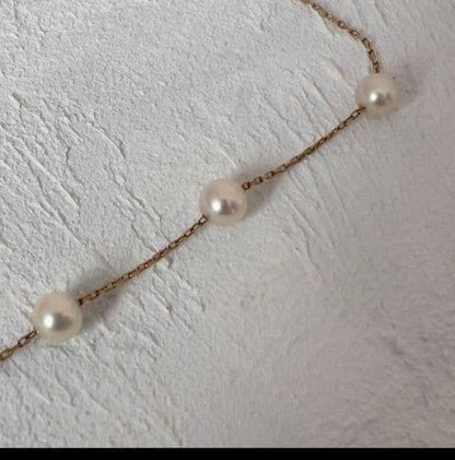 Beautiful K18 gold chain Akoya pearl necklace with 13 round pearls sized 6.5 to 9.5 mm on a white background