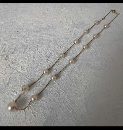 Beautiful K18 gold chain Akoya pearl necklace with 13 round pearls sized 6.5 to 9.5 mm on a white background