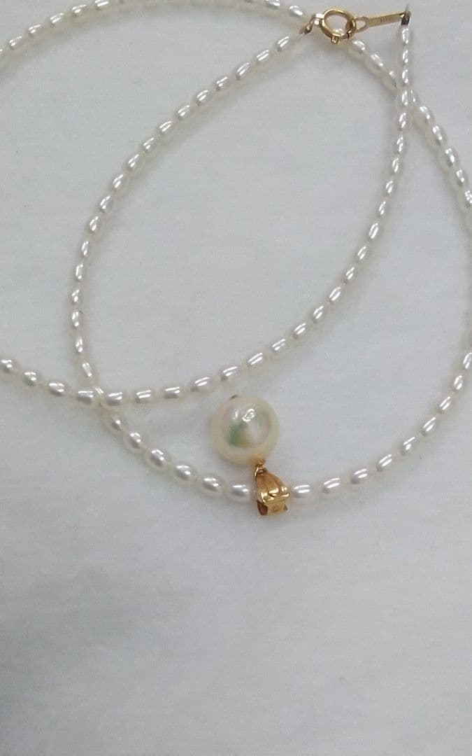 Freshwater Akoya pearl necklace with single 9mm pearl and 18K gold clasp on white background