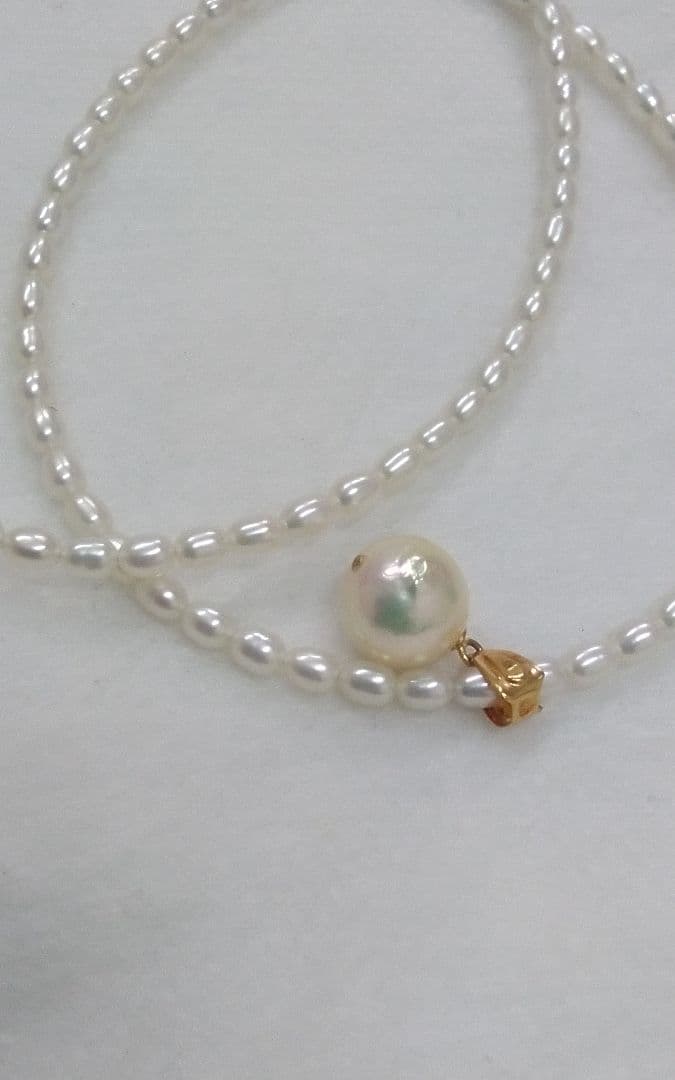 Freshwater Akoya pearl necklace with single 9mm pearl and 18K gold clasp on white background
