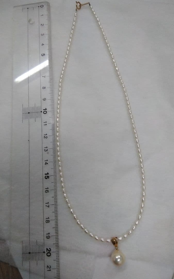 Freshwater Akoya pearl necklace with single 9mm pearl and 18K gold clasp on white background