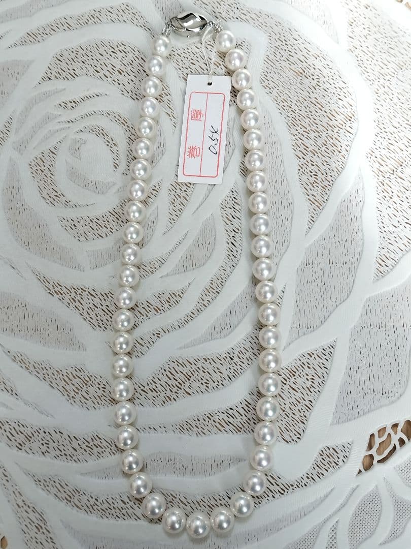 Akoya pearl large round necklace with white pearls and pink-green light interference on a white background