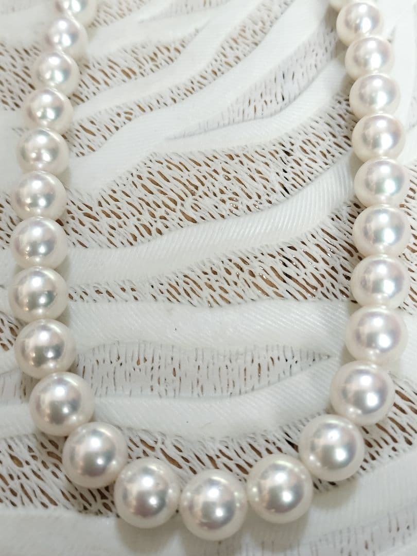 Akoya pearl large round necklace with white pearls and pink-green light interference on a white background