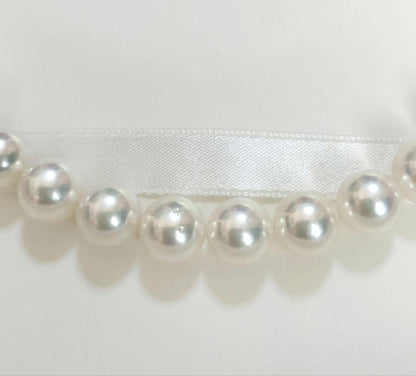 Akoya pearl large round necklace with white pearls and pink-green light interference on a white background