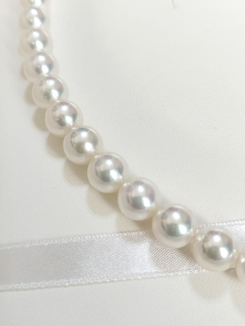 Akoya pearl large round necklace with white pearls and pink-green light interference on a white background