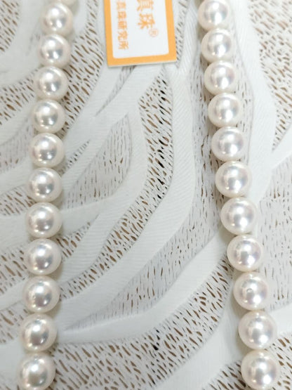 Akoya pearl large round necklace with white pearls and pink-green light interference on a white background
