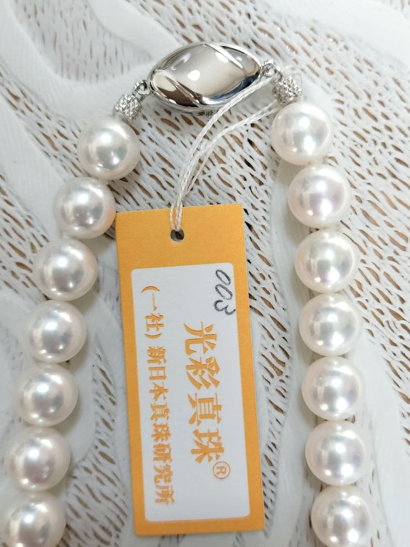 Akoya pearl large round necklace with white pearls and pink-green light interference on a white background