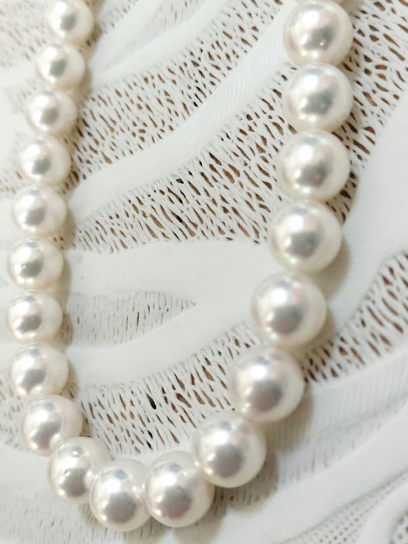 Akoya pearl large round necklace with white pearls and pink-green light interference on a white background