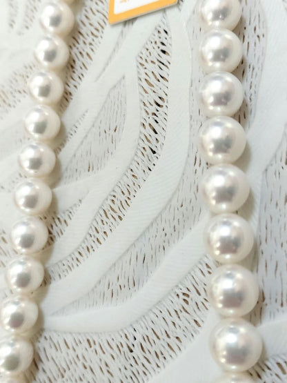 Akoya pearl large round necklace with white pearls and pink-green light interference on a white background