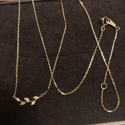Close-up of agate Laurel Leaf K10 necklace featuring small diamonds on a shiny gold chain