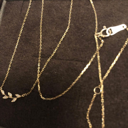 Close-up of agate Laurel Leaf K10 necklace featuring small diamonds on a shiny gold chain